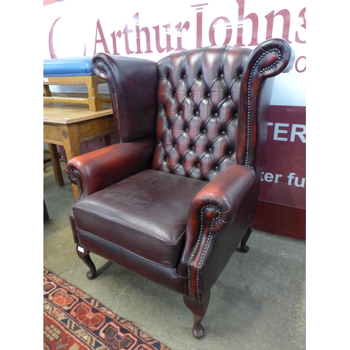 28 - An oxblood red leather Chesterfield wingback armchair