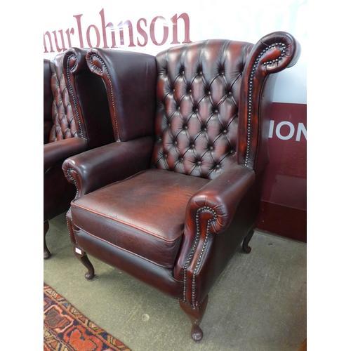 29 - An oxblood red leather Chesterfield wingback armchair