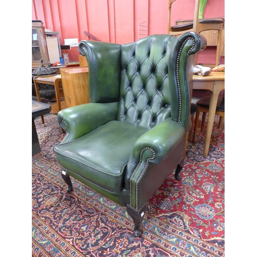 30 - A green leather Chesterfield wingback armchair