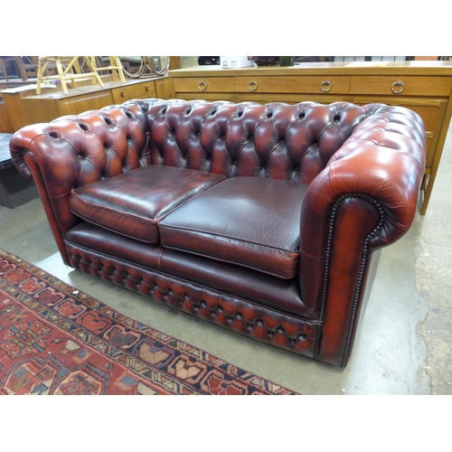 31 - An oxblood red leather Chesterfield settee