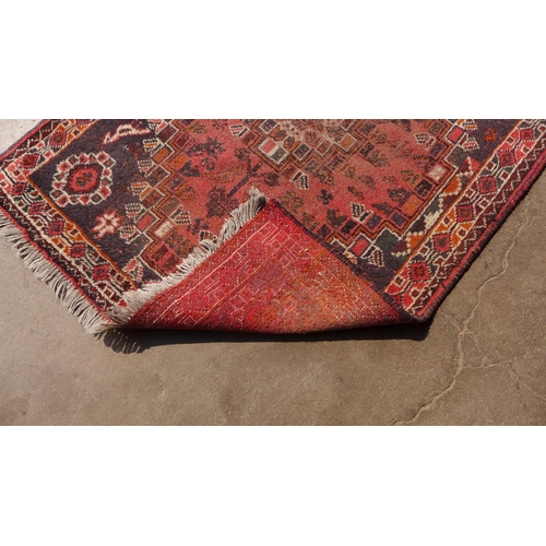 174 - An eastern hand knotted red ground rug