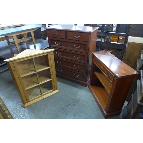 200 - A cherry wood effect chest of drawers, a yew wood bookcase and a pine corner cabinet