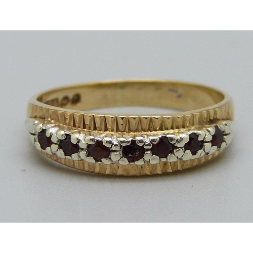 1033 - A 9ct gold, seven red stone ring, 2.2g, L, centre stone a/f