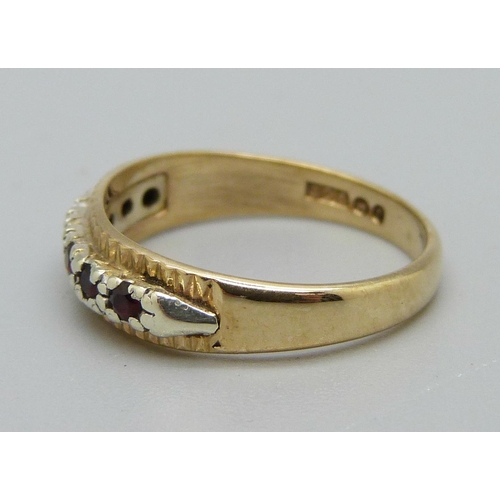 1033 - A 9ct gold, seven red stone ring, 2.2g, L, centre stone a/f