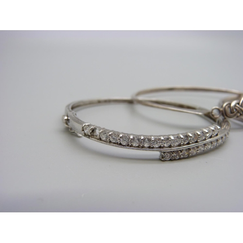 1106 - A 9ct white gold bangle, 3.6g, dented, and four silver bangles, 39g