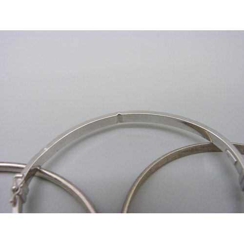 1106 - A 9ct white gold bangle, 3.6g, dented, and four silver bangles, 39g