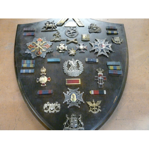 817 - A shield with military related badges, etc.