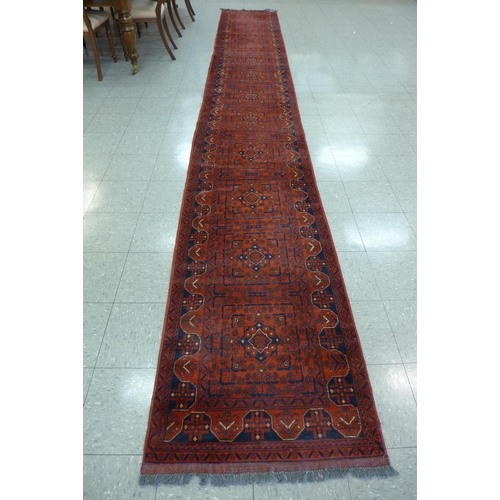 188 - A Turkish hand knotted red ground runner, 582 x 80cms