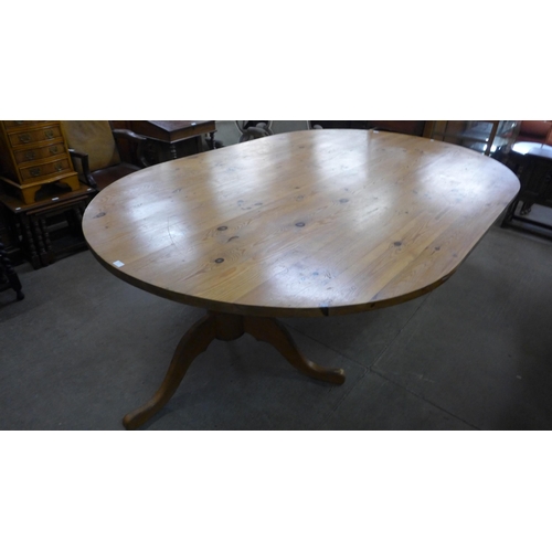 225 - A large oval pine pedestal dining table