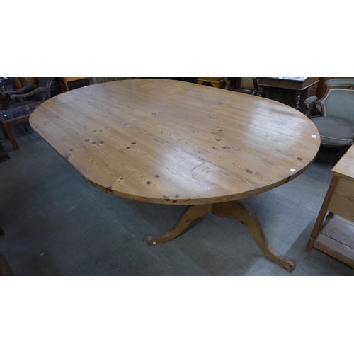 225 - A large oval pine pedestal dining table