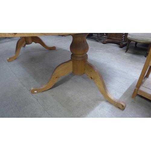 225 - A large oval pine pedestal dining table