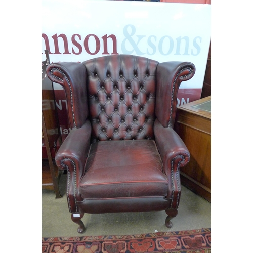 90 - An oxblood red leather Chesterfield wingback armchair