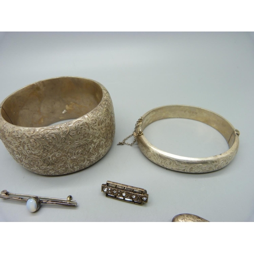 1052 - A silver bangle, a large white metal bangle, three silver lockets, etc.