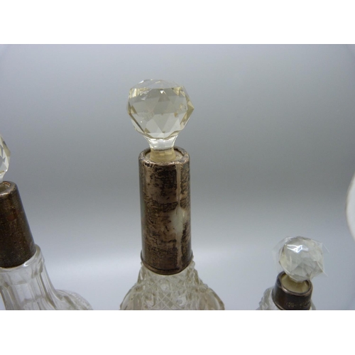 814 - A collection of five silver mounted glass scent bottles, one stopper chipped