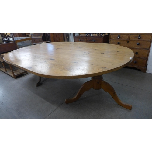 168 - A large oval pine pedestal dining table