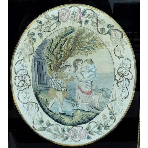 299a - A Regency oval silkwork, depicting a young couple with baby, within a border of flowers and swags, c... 