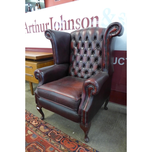 90 - An oxblood red leather Chesterfield wingback armchair