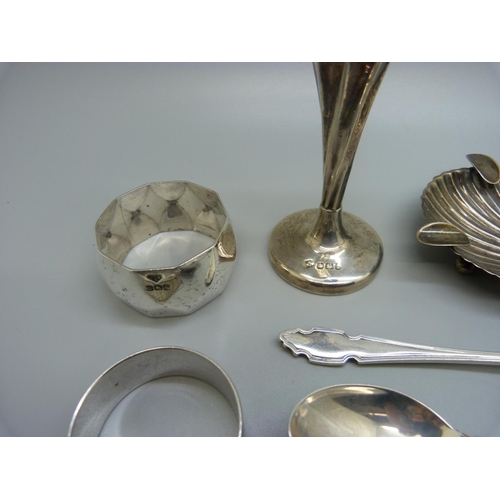 828 - Six silver items; a vase, two napkin rings, dish, a fork and a spoon, and a white metal shell shaped... 