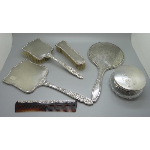 835 - A silver backed hand mirror with two matching brushes, one other silver backed hand mirror, a silver... 