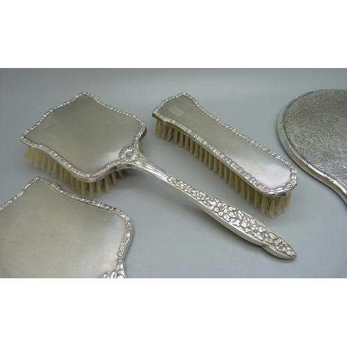 835 - A silver backed hand mirror with two matching brushes, one other silver backed hand mirror, a silver... 