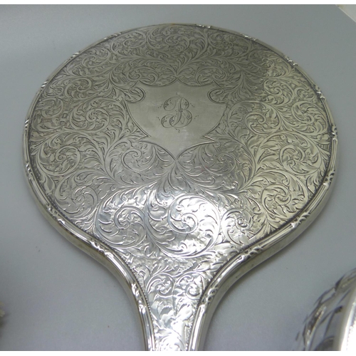 835 - A silver backed hand mirror with two matching brushes, one other silver backed hand mirror, a silver... 