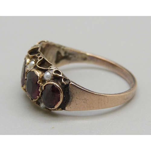 903 - A c1900 yellow metal garnet and seed pearl ring, 1.8g, L