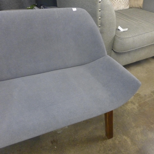 1530 - A grey fabric three seater bench with dark oak legs