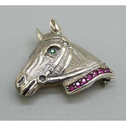 1022 - A silver horses head brooch set with rubies and emerald eye