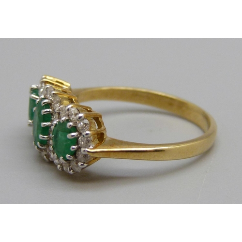 1038 - An 18ct gold, emerald and diamond triple cluster ring, 0.50ct diamond weight marked in the shaft, 3.... 