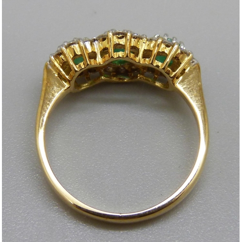 1038 - An 18ct gold, emerald and diamond triple cluster ring, 0.50ct diamond weight marked in the shaft, 3.... 