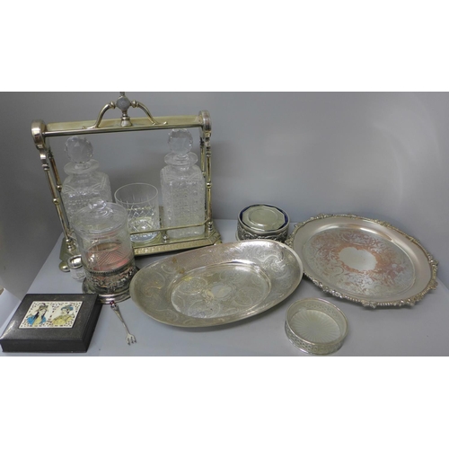 730 - A plated three bottle tantalus stand with two decanters only and a large whisky glass, a plated tray... 