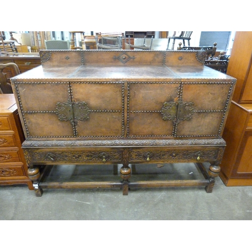 117 - An Elizabethan Revival carved oak and nailed brown leather sideboard