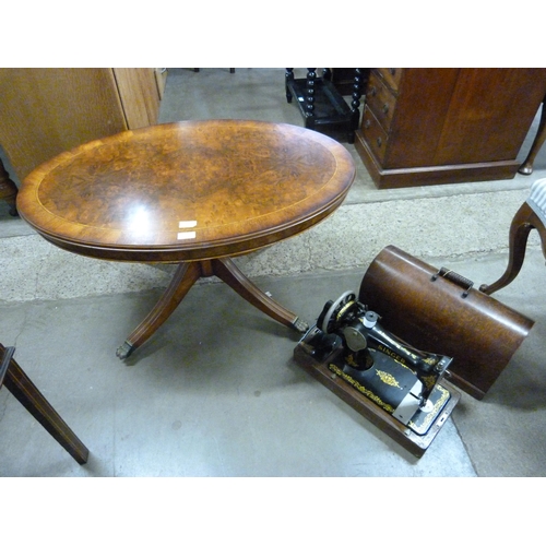 191 - A figured walnut oval coffee table and a cased Singer sewing machine