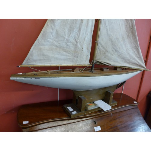 289 - A wooden Sam sized yacht, with canvas sail and display stand, 85cms l, 135cms h