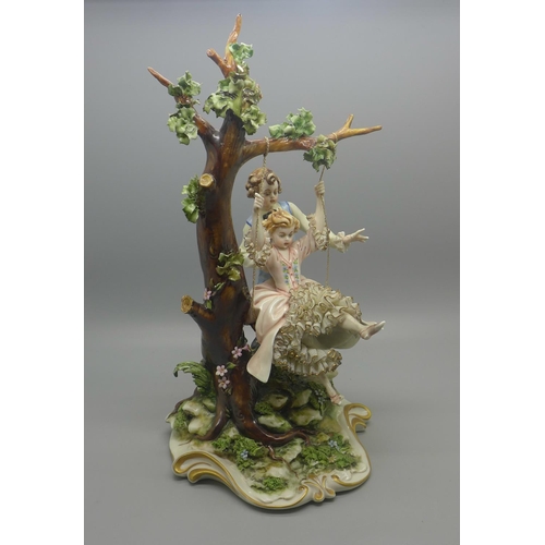 613 - A Neapolitan figure of a boy pushing a girl on a swing, small chip to back of base, 29cm