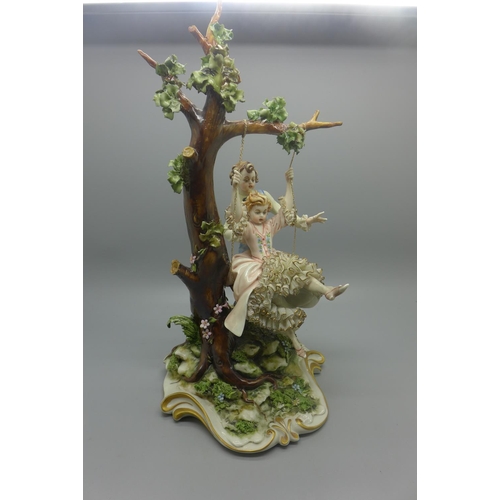 613 - A Neapolitan figure of a boy pushing a girl on a swing, small chip to back of base, 29cm