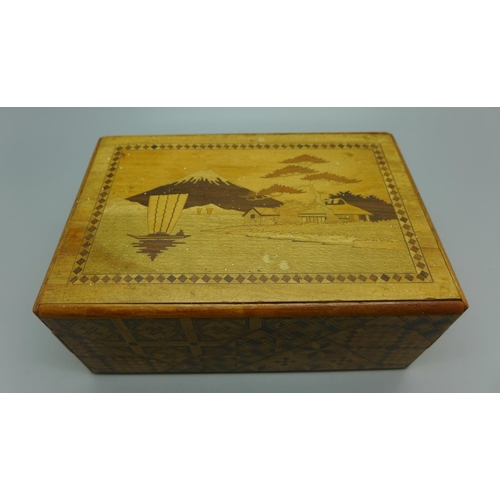 652 - A Japanese marquetry inlaid puzzle box, one side cracked