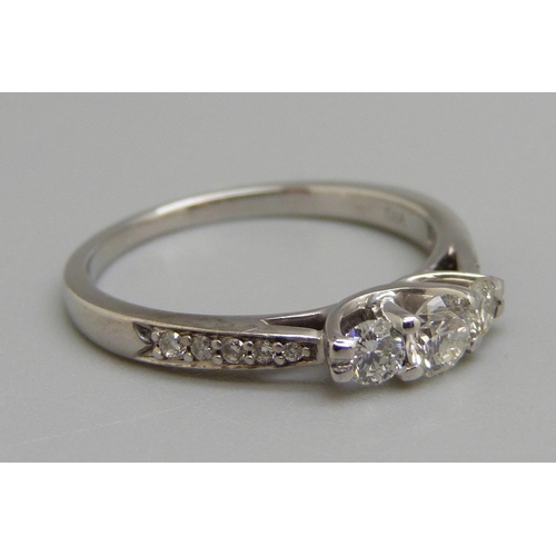 965 - An 18ct white gold three stone diamond ring with diamond shoulders, N, 2.9g, shank marked 0.50ct