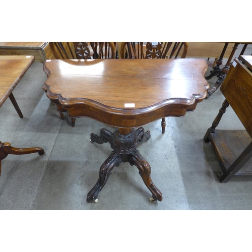 114 - An early Victorian carved rosewood serpentine fold over games table