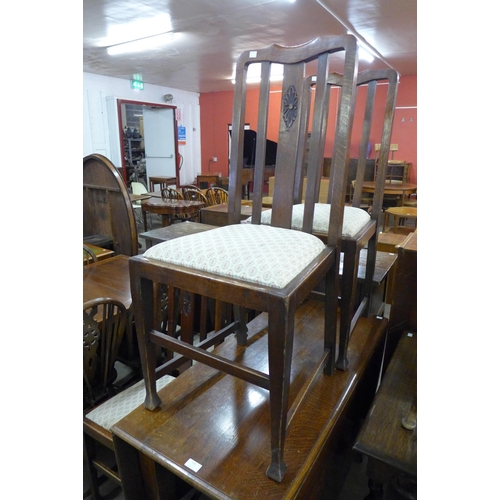 126 - An early 20th Century oak drop leaf dining table and four chairs