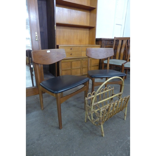 87 - A pair of teak and black vinyl chairs and a bamboo magazine rack