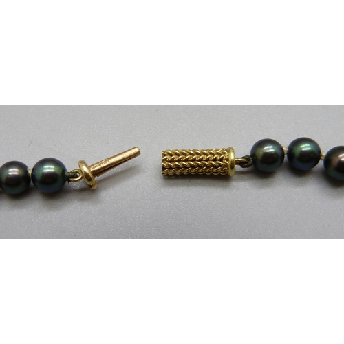 1021 - A string of black pearls with a yellow metal clasp, continental control mark