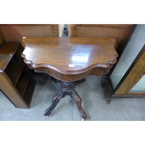 173 - An early Victorian carved rosewood serpentine fold over games table