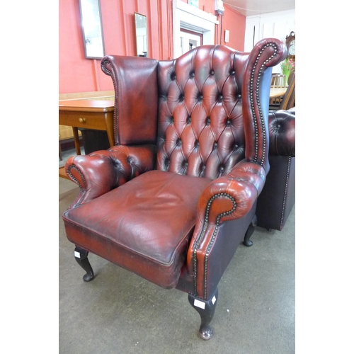 69 - An oxblood red leather Chesterfield wingback armchair