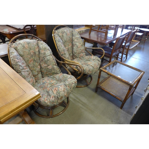 221 - A pair of bamboo revolving armchairs and matching occasional table