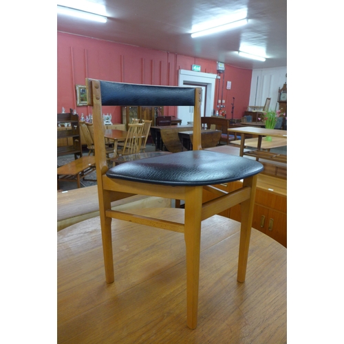 77 - A circular teak extending dining table and three chairs