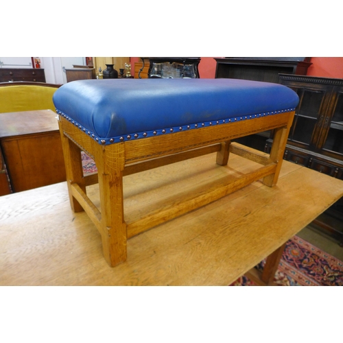 39 - A Cotswold School Arts and Crafts oak and blue vinyl upholstered foot stool