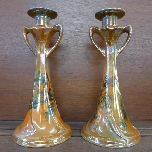 606 - A pair of Shelley England orange lustre candlesticks with countryside scenes, 26.5cm