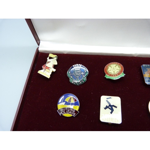 831 - Nine Butlins pin badges, with case