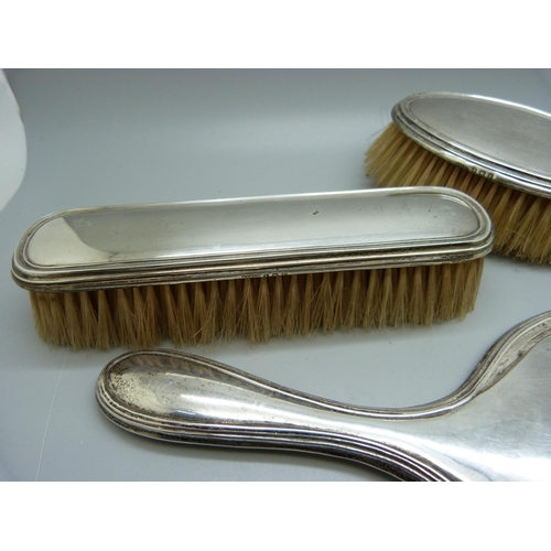 868 - A silver backed mirror and two brushes